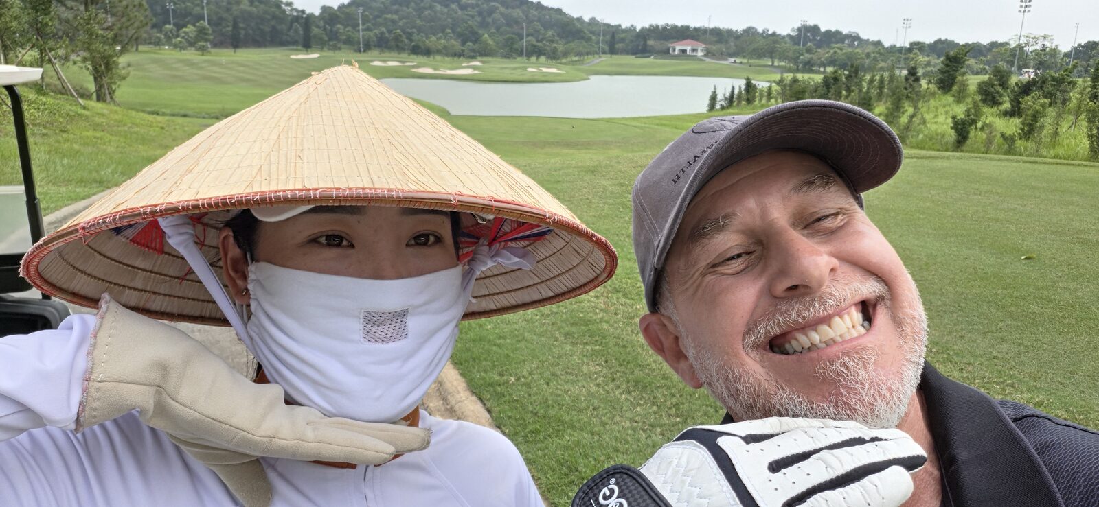 Selfie with a caddie in a conical hat on the course