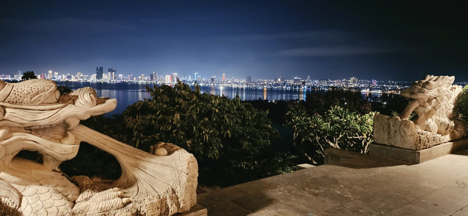 Stone dragon statues overlooking the bay at night