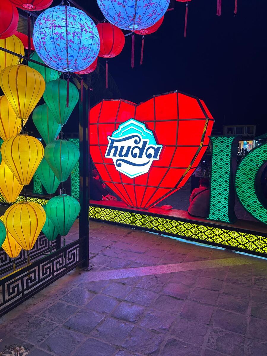 Giant illuminated Huda beer heart sign among colourful lanterns at night